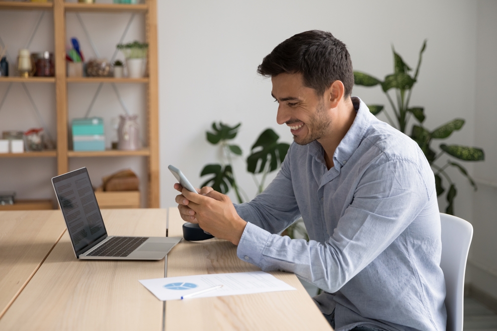 Smiling,35s,Hispanic,Businessman,,Office,Employee,Hold,Cellphone,Sit,At