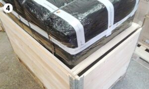 black-wrapped item placed inside partially assembled wooden shipping crate